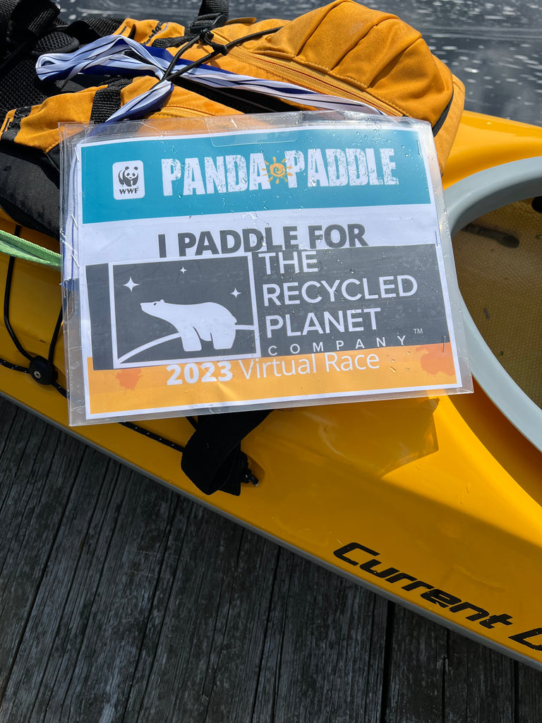 Kayak on lake with sign that says "I paddle for The Recycled Planet Company 2023 WWF Panda Paddle Virtual Race"